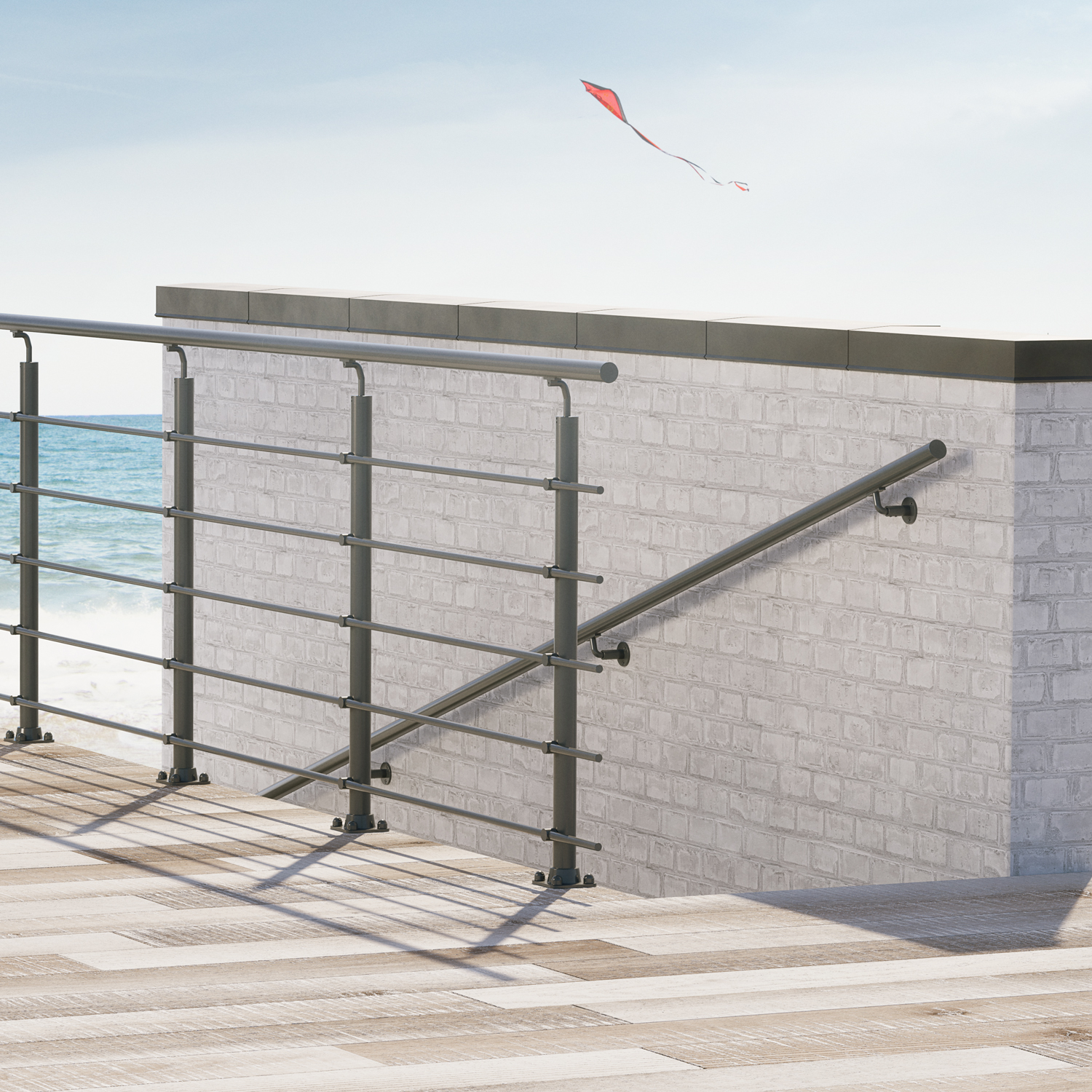Corrimano e parapetto in metallo su una terrazza sul mare con muri in mattoni bianchi, affacciata sull’oceano con un aquilone sullo sfondo.