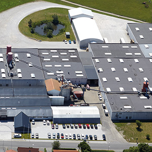 Vista aerea della sede centrale Dolle in Danimarca, con un grande stabilimento, parcheggi e aree verdi circostanti.