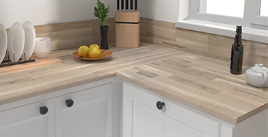 Piano di lavoro da cucina moderno in legno chiaro, arricchito da barattoli e utensili per un’estetica naturale e funzionale.