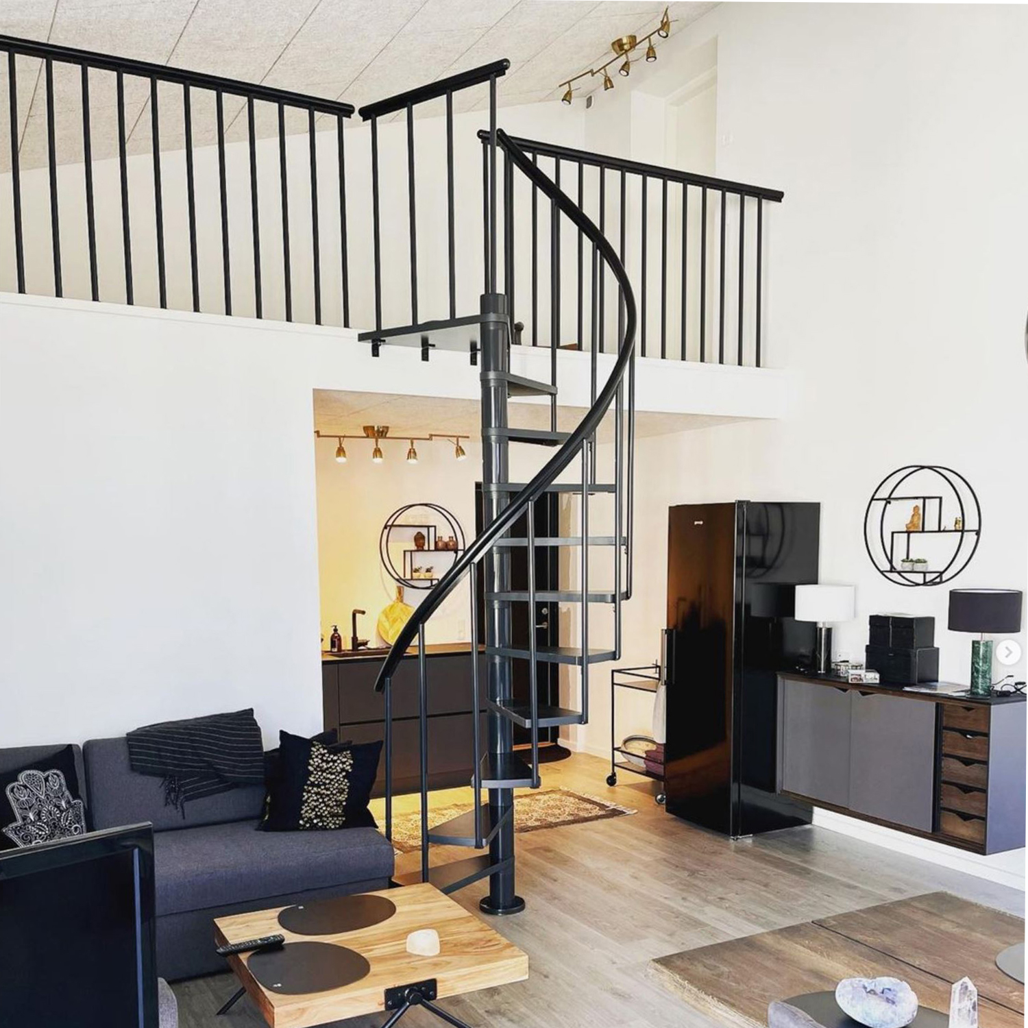 Scala a chiocciola in metallo nero in un soggiorno contemporaneo con decorazione moderna.