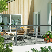 Balcone esterno con balaustre in vetro e corrimano, circondato da vegetazione e piante in vaso.
