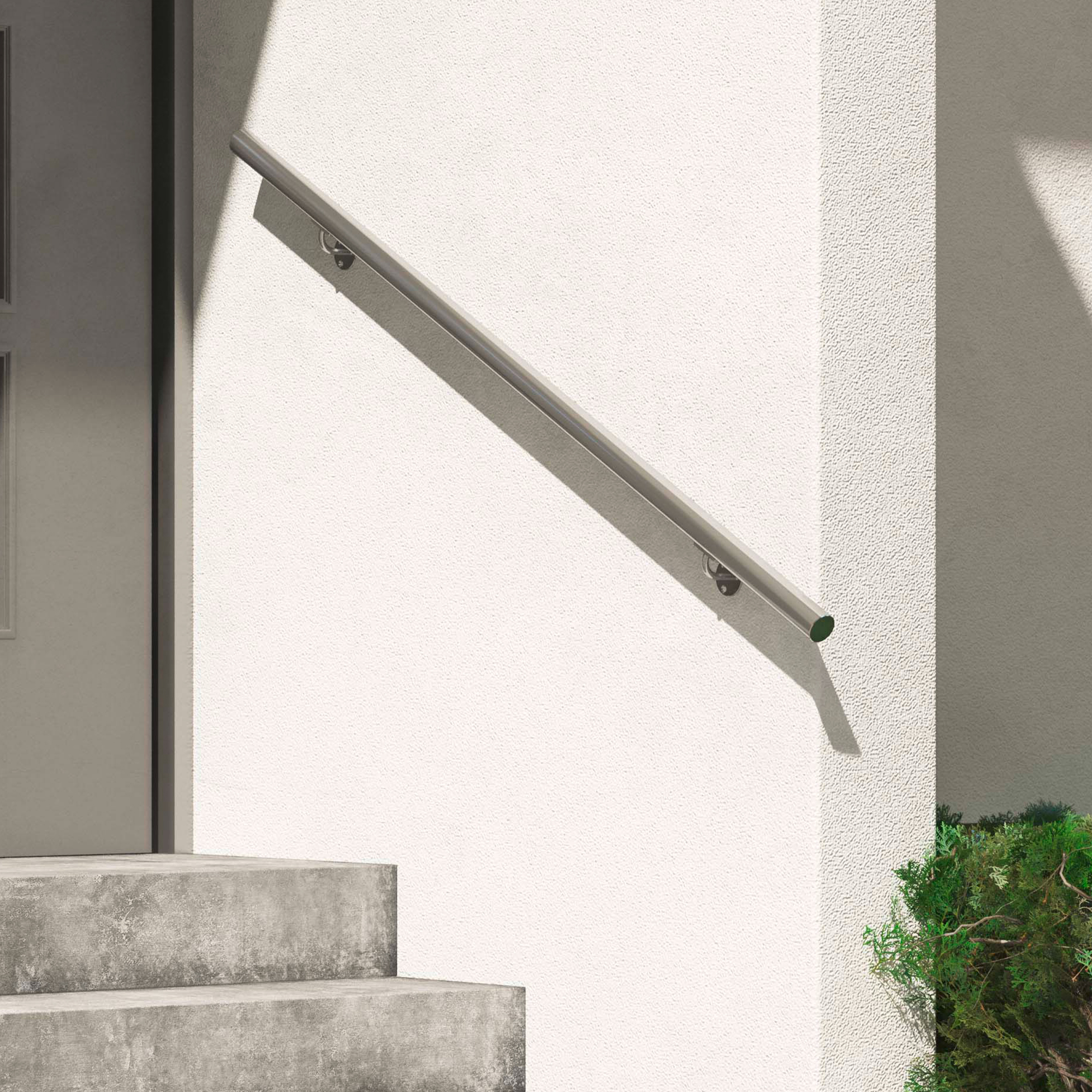 Corrimano in metallo minimalista su una parete esterna bianca, accanto a gradini in cemento e vegetazione.