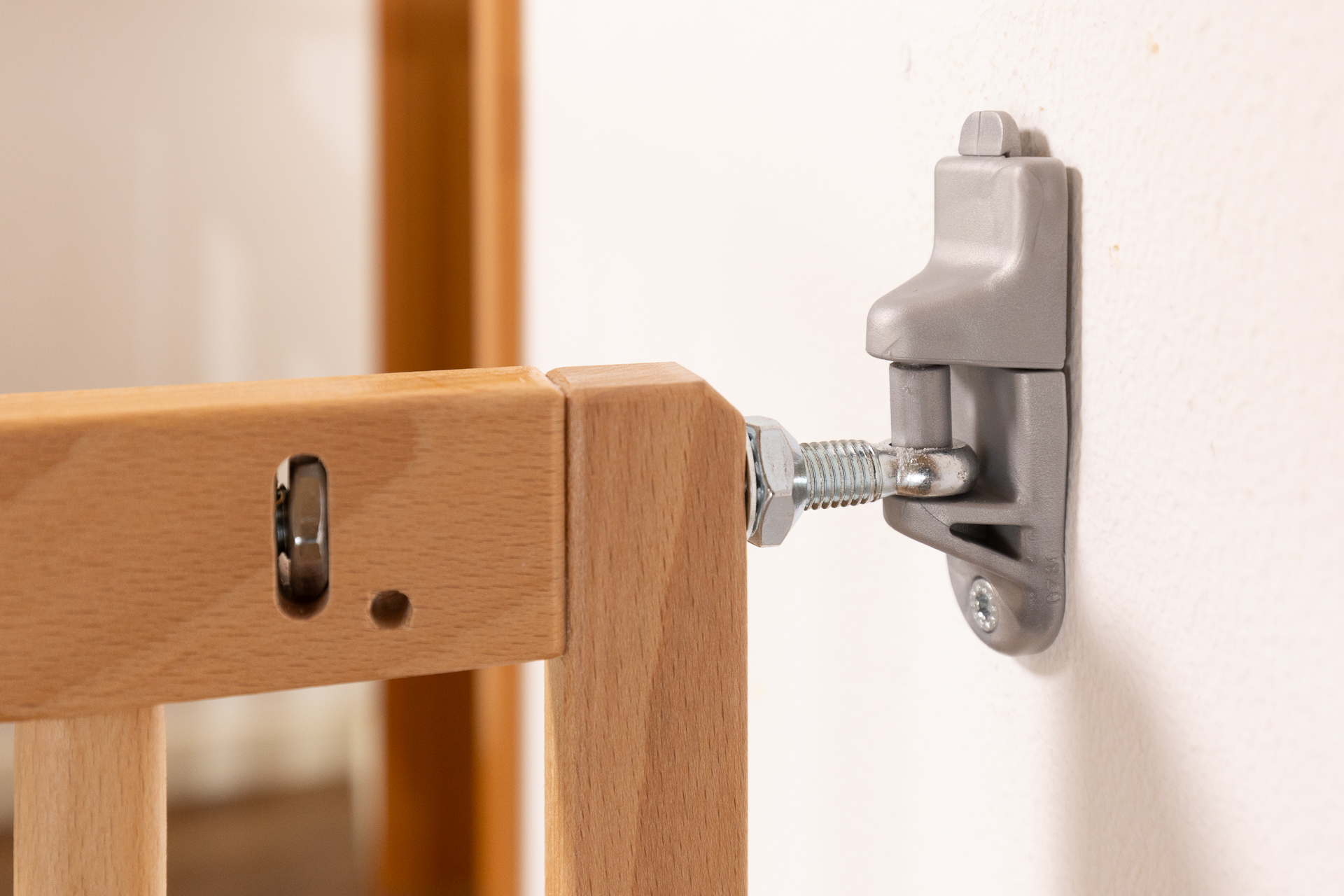 Sistema di fissaggio metallico di un cancelletto di sicurezza in legno SOGEM, saldamente avvitato alla parete, con vite di regolazione visibile.